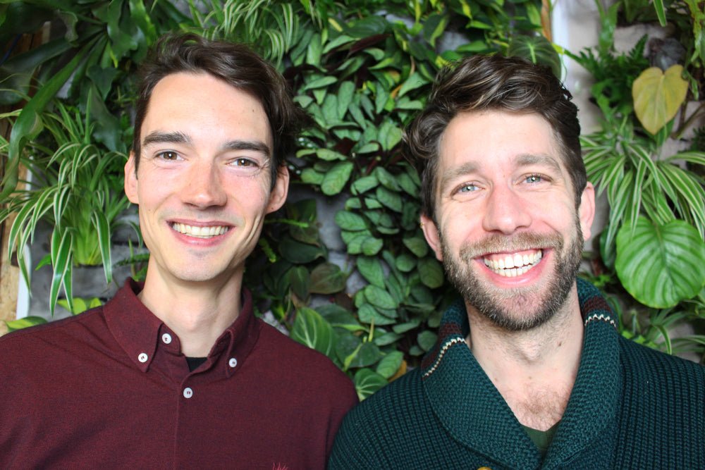 De oprichters van Billiwild lachend voor een muur vol planten